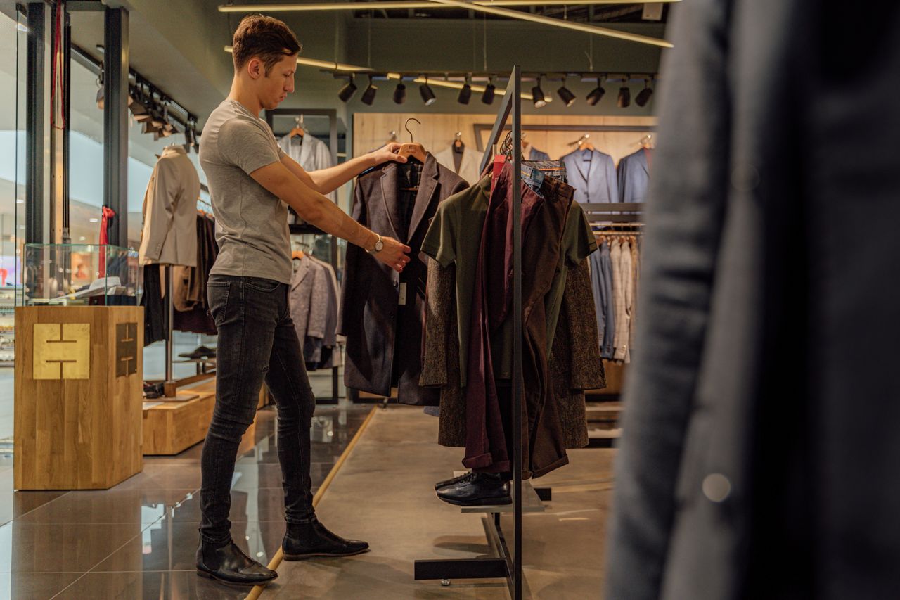 Services A man browsing stylish blazers in a modern clothing store, focusing on mens fashion.